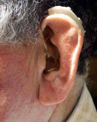 Un anciano con su aparato de audición en su oido